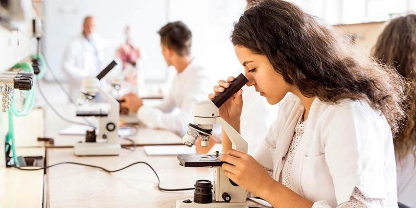 一名学生在获得CT生物学学位时正在看显微镜